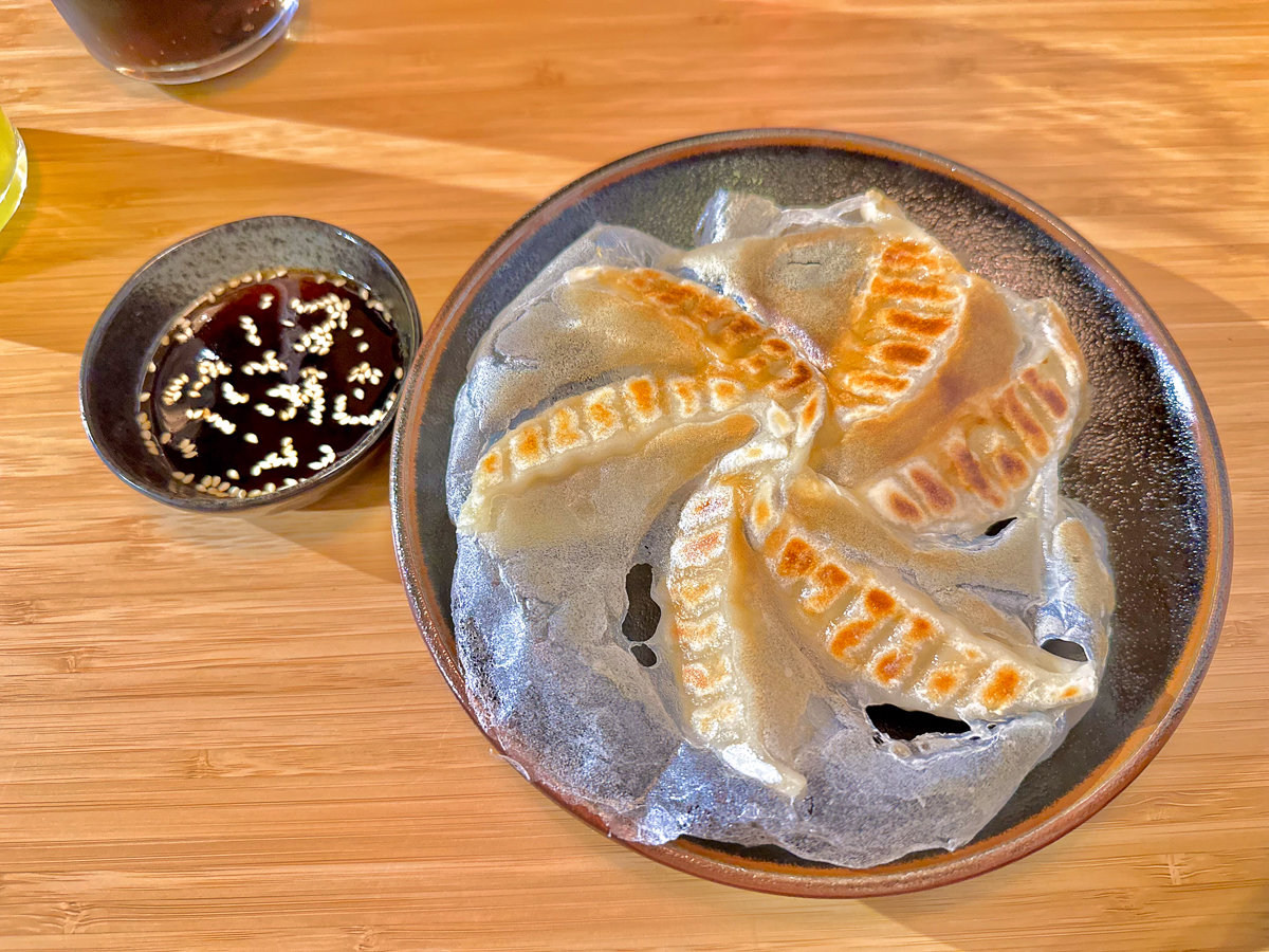 gyoza dumplings with brown dipping sauce on a brown table